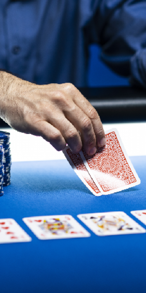 Man playing Texas Hold'em Poker with chips and community cards on blue tabletop