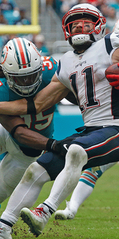Walt Aikens #35 of the Miami Dolphins tackles Julian Edelman #11 of the New England Patriots as he runs with the ball during an NFL game on December 9, 2018 at Hard Rock Stadium in Miami Gardens, Florida. The Dolphins defeated the Patriots 34-33.