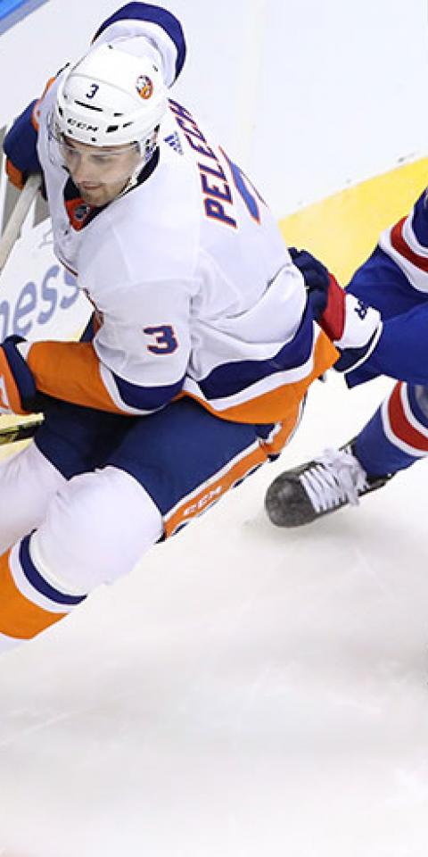 Adam Pelech #3 of the New York Islanders wraps around the net as Brett Howden #21 of the New York Rangers.